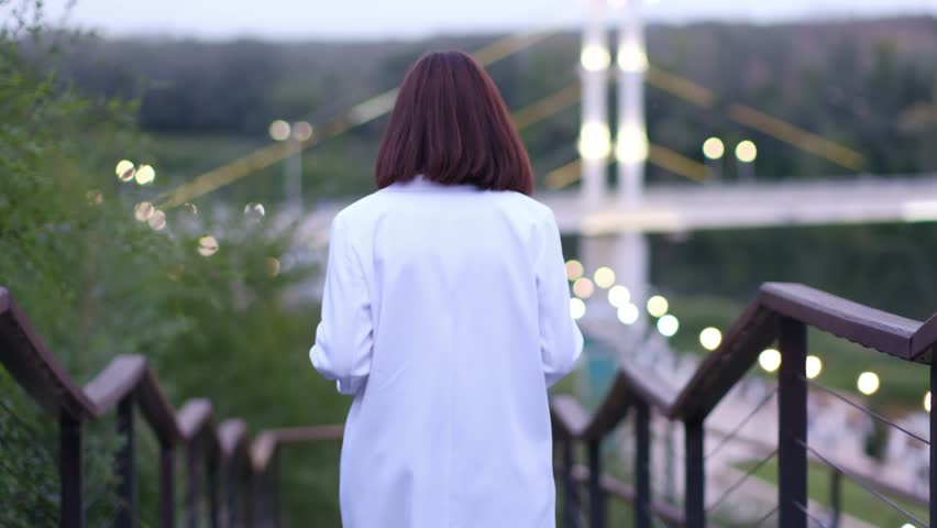 a fasionable woman in a white suit walking down the stairs by her back outdoor.