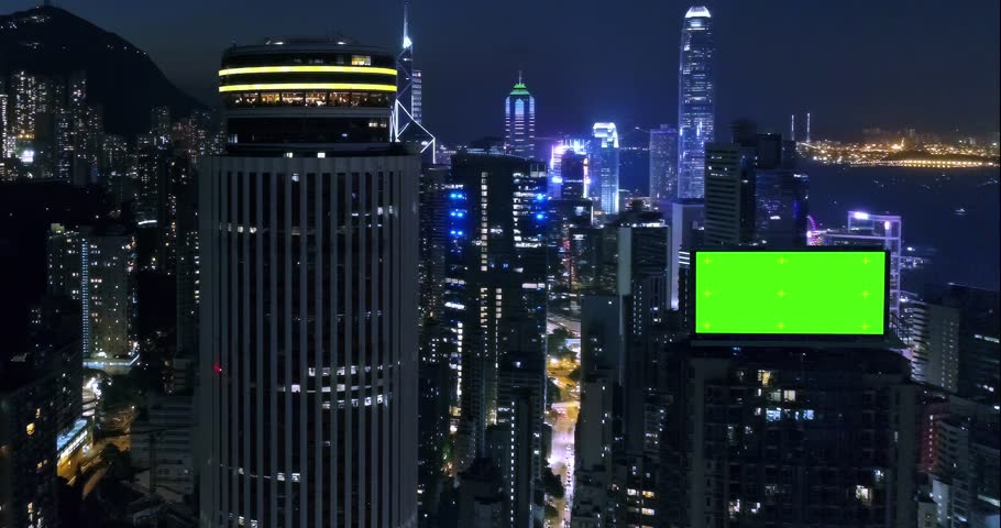 AERIAL. Top view of skyscrapers and green screen build board with tracking point. Bird view of modern city at night streets. Royalty-Free Stock Footage #1108628085