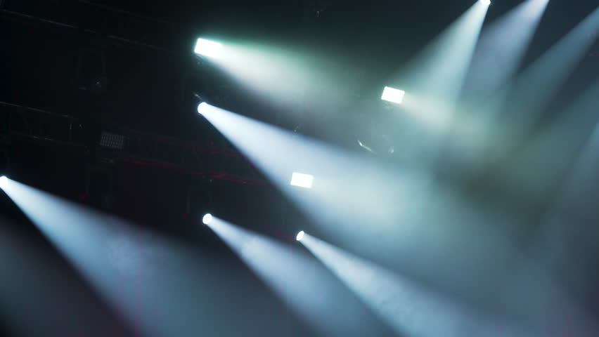 Many spotlights illuminate concert stage. Colorful spot light effect. Cool theater lighting show. Bright spotlight projector shines scene. Atmosphere nightclub party. Epic disco background. Shiny beam