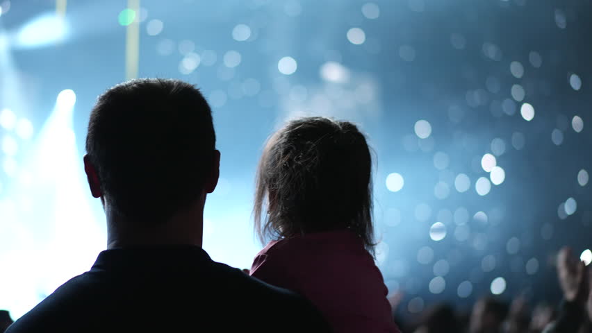 Happy little girl sit on her dad. Small kid have fun live music concert. Cool blue glitter night. Child enjoy disco party. Joy childhood. Daughter hang out pop show. Family band fan. People raise up.
