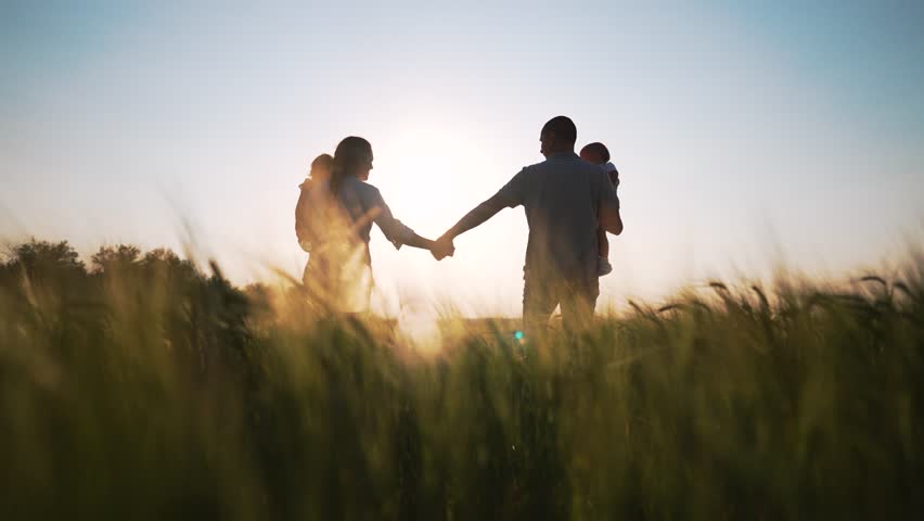 Silhouette of young happy family in wheat field walk at sunset in summer. Happy family concept.An active family of parents with toddlers walks in wheat field at sunset.Hiking in the countryside picnic Royalty-Free Stock Footage #1108639321