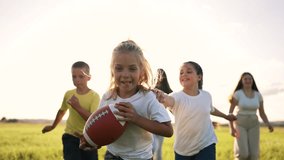 Group of children with rugby ball play American football. In summer, team of kid in nature plays with an american football rugby ball. Kid run in park at sunset. Team of children together in nature - Powered by Shutterstock - Get 15% off with code: PIKWIZARD15