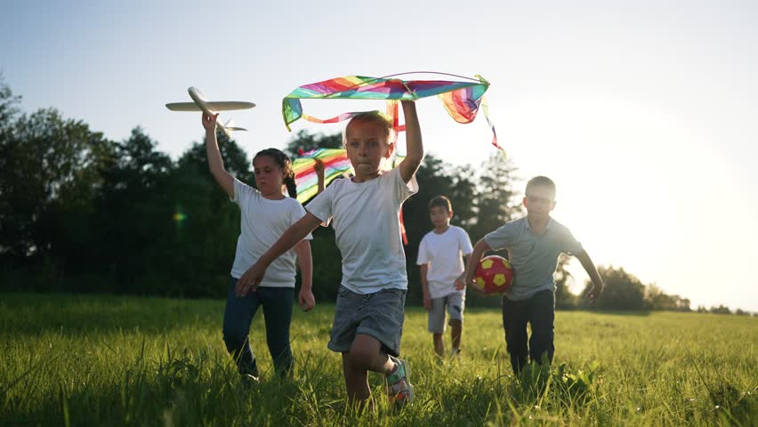 happy family.Little children run with kite along green grass in park in nature.Summer game for child on vacation with kite.Kid run in nature with kite in summer.Freedom and dream of children in park Royalty-Free Stock Footage #1108639349
