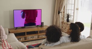 Biracial family watching tv with african american male rugby player with ball on screen. Communication technology and sports, digital composite video.