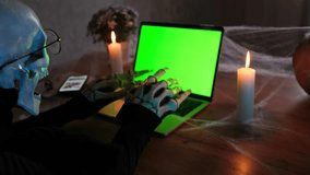 Side view man in costume death skeleton at laptop with chromakey and type scary posts and scary stories on keyboard. Celebrating holiday Halloween. Horror-loving friends to scariest Halloween party  - Powered by Shutterstock - Get 15% off with code: PIKWIZARD15