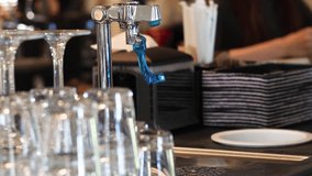 Close up of pouring water into a clear glass,  free clean water in caffe catering 4K video. Silver water tap, drinks container.