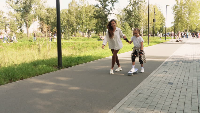 Caucasian mother and daughter riding skateboards. Fun joy emotions of tenderness love care. Laugh rejoice game
