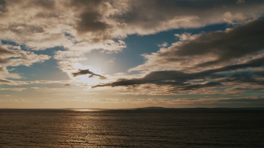 Cinematic View of a Beautiful Dramatic Sea Sunset with Clouds. Burning Sky and Shining Golden Waves. Sunset Horizon Over the Ocean. Beautiful Evening Sunset in the Sky Over the Ocean.