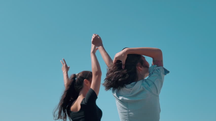 Two asian Women raise hands reach out to sun at sunset. Happy friends together spend time at vacation holidays. Teamwork. Enjoy summer freedom travel. Friendship, joy of life, cheers concept.