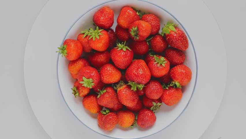 Juicy red strawberries in a white plate rotate in a circle on a white background top view. Close up | Shutterstock HD Video #1108657485