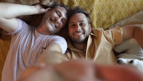 homosexual couple recording an overhead video lying in bed