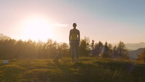 CLOSE UP, LENS FLARE: Lady with a dog admires spectacular sunset at the hilltop. She is rewarding herself with an outstanding view of high mountains in golden light after trail running up the hill. - Powered by Shutterstock - Get 15% off with code: PIKWIZARD15