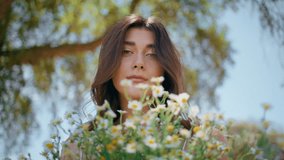 Portrait countryside model hold flowers in rural nature. Closeup smiling lady face with fresh spring camomiles bouquet at blue sky background. Romantic woman enjoying gentle wildflowers touching hair - Powered by Shutterstock - Get 15% off with code: PIKWIZARD15