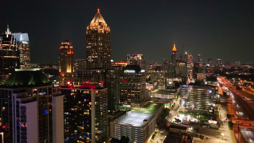 Atlanta, Georgia USA - 8 25 2023: Aerial night footage of Atlanta skyline and highways, cars and builds shot from drone. Glowing buildings against the night sky. View of Atlanta Georgia, U.S.A. Color 