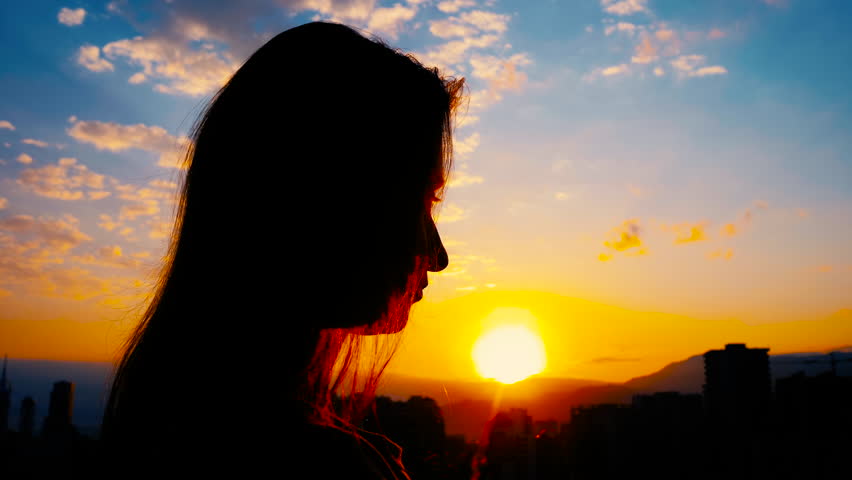 Close up: woman silhouette is folding hands and praying against the sunrise or sunset sky over the city: side view, sun lens flares. Religion, prayer gesture, hope, spiritual and nature concept Royalty-Free Stock Footage #1108668971
