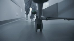 Doctor or paramedic runs and pushes gurney with seriously injured patient towards surgery room. Medic save human life. Close up of medical staff legs. Bright hospital corridor. Emergency department. - Powered by Shutterstock - Get 15% off with code: PIKWIZARD15