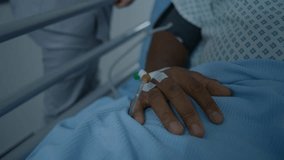 African American patient lies on gurney with catheter on hand. Nurse transports man to hospital room down medical center corridor after surgery. Medical staff at work in modern clinic. Close up. - Powered by Shutterstock - Get 15% off with code: PIKWIZARD15