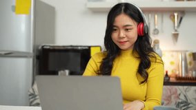 Cheerful Asian woman in headset laughing happily Listen to music, relax, use your laptop, stream video conference calls, teach online. hobby ideas work from home