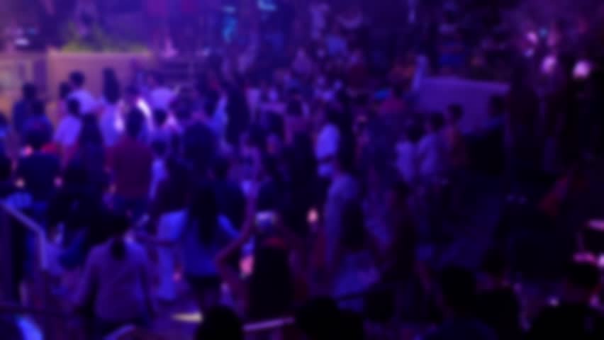 Out of focus of Crowd people making party at a concert disco nightclub. People dancing at party in club full with light illumination onboard cruise ship.Happy people dance in nightclub party concert