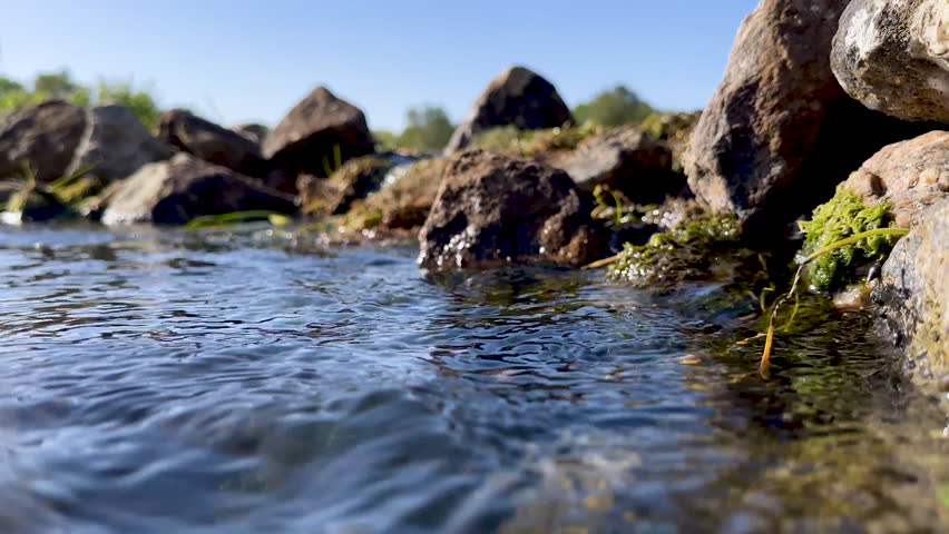Camera moves from mountain stones - descends under water on river with swaying algae and clear fresh water with air bubbles | Shutterstock HD Video #1108676247
