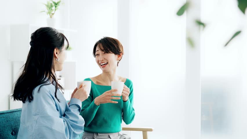 Two Asian women chatting while drinking tea.