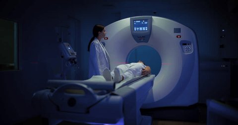 In Medical Laboratory, Radiologist Controls MRI or CT or PET Scan with Patient Undergoing Procedure. Professional Female Doctor Conducts Emergency Check Up Procedure with Advanced Medical Technologies स्टॉक व्हिडिओ