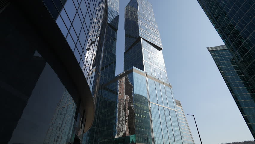 The mirrored facade of the Moscow City business center in the reflection of other skyscrapers. The glare of the sun in the reflection of mirrored modern buildings. Dolly camera Royalty-Free Stock Footage #1108681763