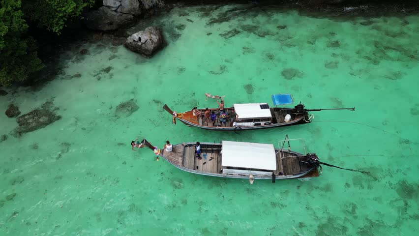 Two swaying boats on clear turquoise water, island hopping, Phi Phi, Pileh lagoon. Top view, stones, bottom, mountain landscape, corals, longtails. High quality 4k footage Royalty-Free Stock Footage #1108681875
