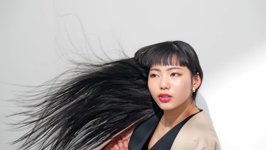 Beautiful young Asian woman with long black hair blowing in the wind.  Hair care concept.