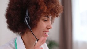 Close up of african american medical worker talking in microphone of wireless headset during online meeting with patient. Concept of telemedicine consultations and modern technology.