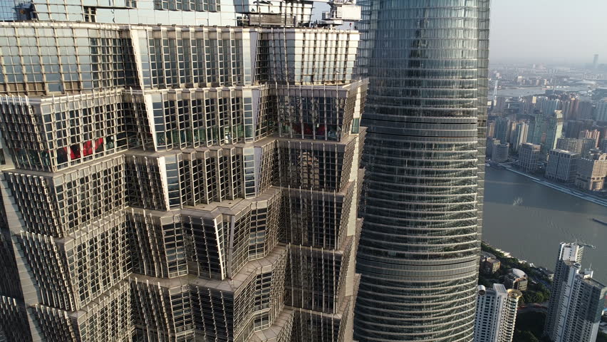 Close drone flight past iconic Jin Mao skyscraper commercial office tower, reflection of Oriental Pearl Tower in World Financial Center building, Shanghai skyline, architecture China
