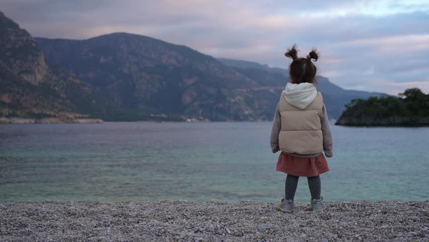 A Little Baby Girl Stands Dreamily on the Seashore and Looks into the Distance Royalty-Free Stock Footage #1108692483