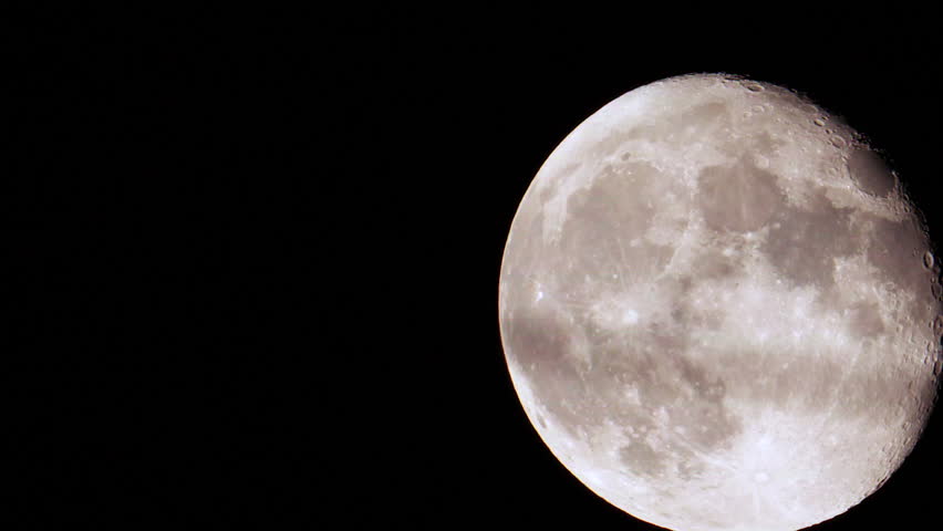 A new mid summer full super moon climbs higher into the dark summer night sky, seen from suburban section of the north eastern megalopolis in north america with moderate light dome pollution overhead 