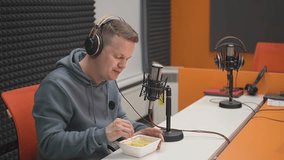 a man wearing headphones eats instant noodles.instant noodles. recording audiobooks. Record high quality video in Full HD format.