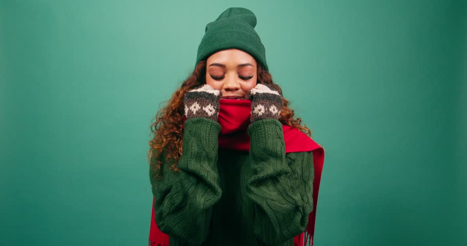 Freezing cold woman bundles up against the cold, huddles in warm scarf, studio