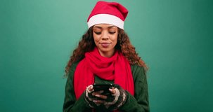 Young woman looks to camera and smiles, texting friends over Christmas, studio