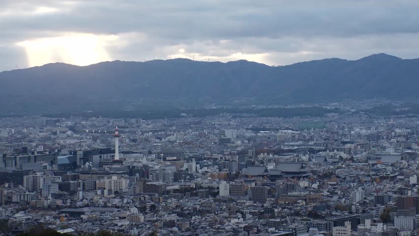 KYOTO, JAPAN - DECEMBER 2021 : Aerial high angle sunset view of Kyoto city. Scenery of mountain, streets and buildings around central downtown area. Long time lapse shot, dusk to night.