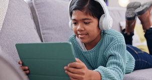 Girl, kid and tablet, headphones and funny video with internet connection, relax on sofa at family home with tech. Comedy, film and subscription with streaming, audio and laughing with app in lounge