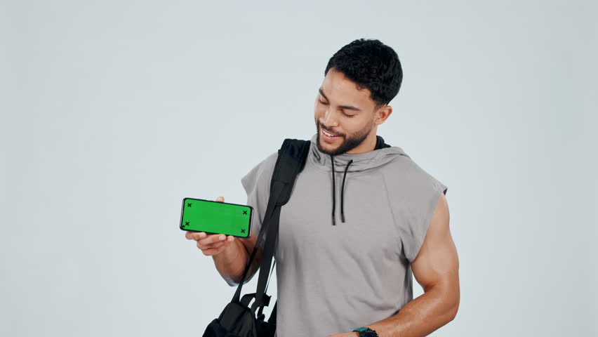 Fit man, phone and pointing to green screen, app or mockup for fitness, gym or sign up against a studio background. Portrait male person with mobile smartphone display for motivation or membership