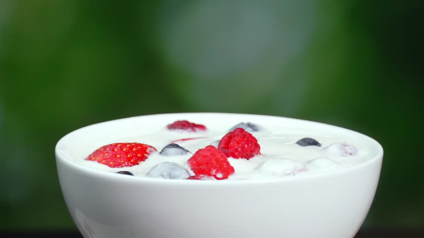 Slow motion of young female hand eating yogurt with spoon with blueberries, raspberries and strawberries. Take spoonful of kefir, delicious and fresh natural yogurt with taste of wild berries | Shutterstock HD Video #1108709361