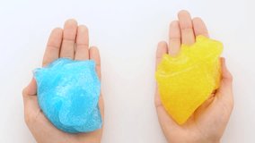 Asmr. Multicolored mucus slowly spreads in the palms of a person. Sticky, yellow, blue jelly-like substances swell in the hands. View from above. A sticky, soothing, relaxing video.