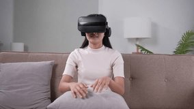 Young woman testing VR glasses or goggles sitting on sofa.