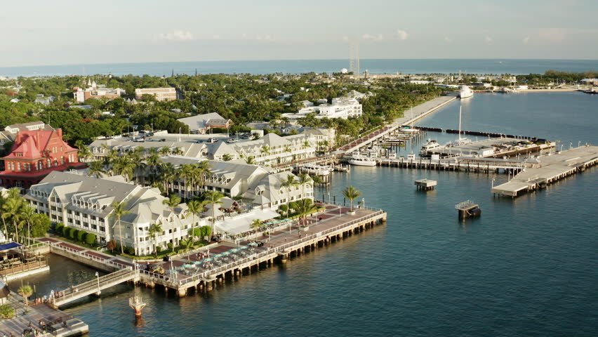 Aerial of the coast of Key west. cinematic low-level drone flyover waterfront resorts and hotels capturing beaches, sunset pier