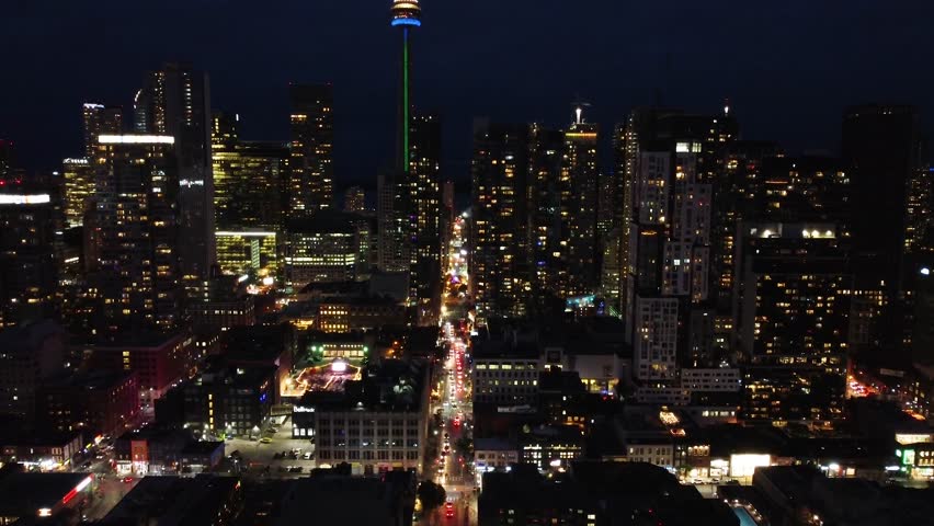 Aerial night drone shot of urban downtown in Toronto, Canada. Drone flying over the financial district with high traffic congestion. Slow camera movement forward. Illuminated and modern cityscape.