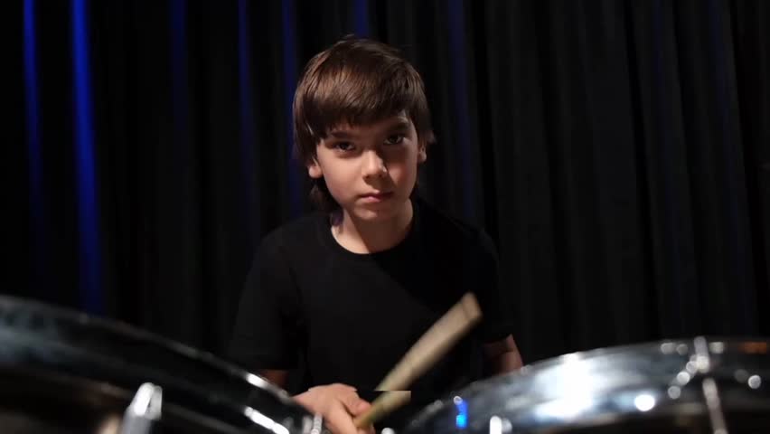 The boy learns to play the drums in the studio on a black background. Music school student Royalty-Free Stock Footage #1108719457