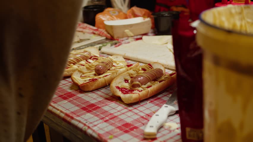 Cooking hot dogs in outdoor fast food restaurant, takeaway festival food truck. Sausages frankfurt and buns are fried and grill for delivery