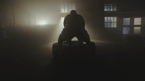 Fit muscular man doing crossfit exercises working out lifting a large rubber tyre in a gym. Low angle back view and slow-motion shot - Powered by Shutterstock - Get 15% off with code: PIKWIZARD15