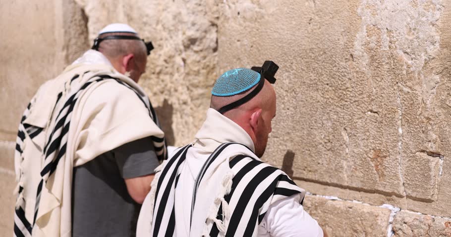 Jews praying. Orthodox Jew facing the Western wall while praying. Other religious men in the background pray to the Kotel. Wailing wall Jerusalem, Jerusalem, Israel. God religion and conflict Royalty-Free Stock Footage #1108731599