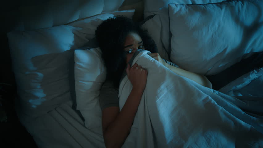 African american woman lying on bed night nightfall dark home bedroom frightened girl scared of ghost hiding under blanket close eyes afraid fantasy monster nightmare fear scary dream phobia insomnia