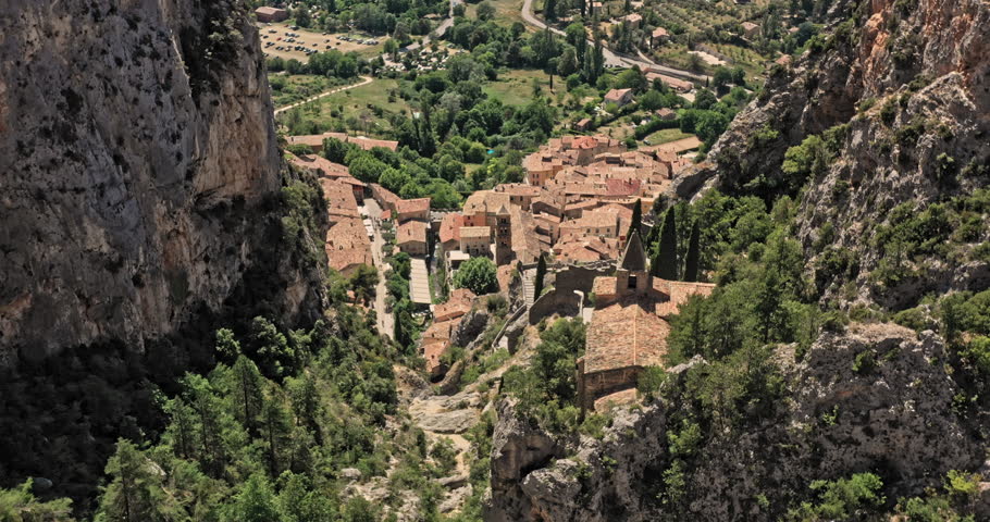 Moustiers Sainte Marie France Aerial v3 cinematic shot drone low level fly through rocky limestone canyon reveals breathtaking middle ages architectures and village townscape - July 2021